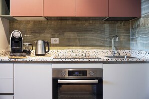 A kitchen with a coffee maker, a kettle, a sink, and an oven. - The City Loft by Riviera Collection (Riccione)
