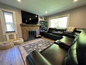 Ein Wohnzimmer mit Kamin, Ledersofa und Flachbildfernseher.