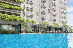 Um hotel moderno com uma grande piscina, área de estar ao ar livre e vegetação exuberante.