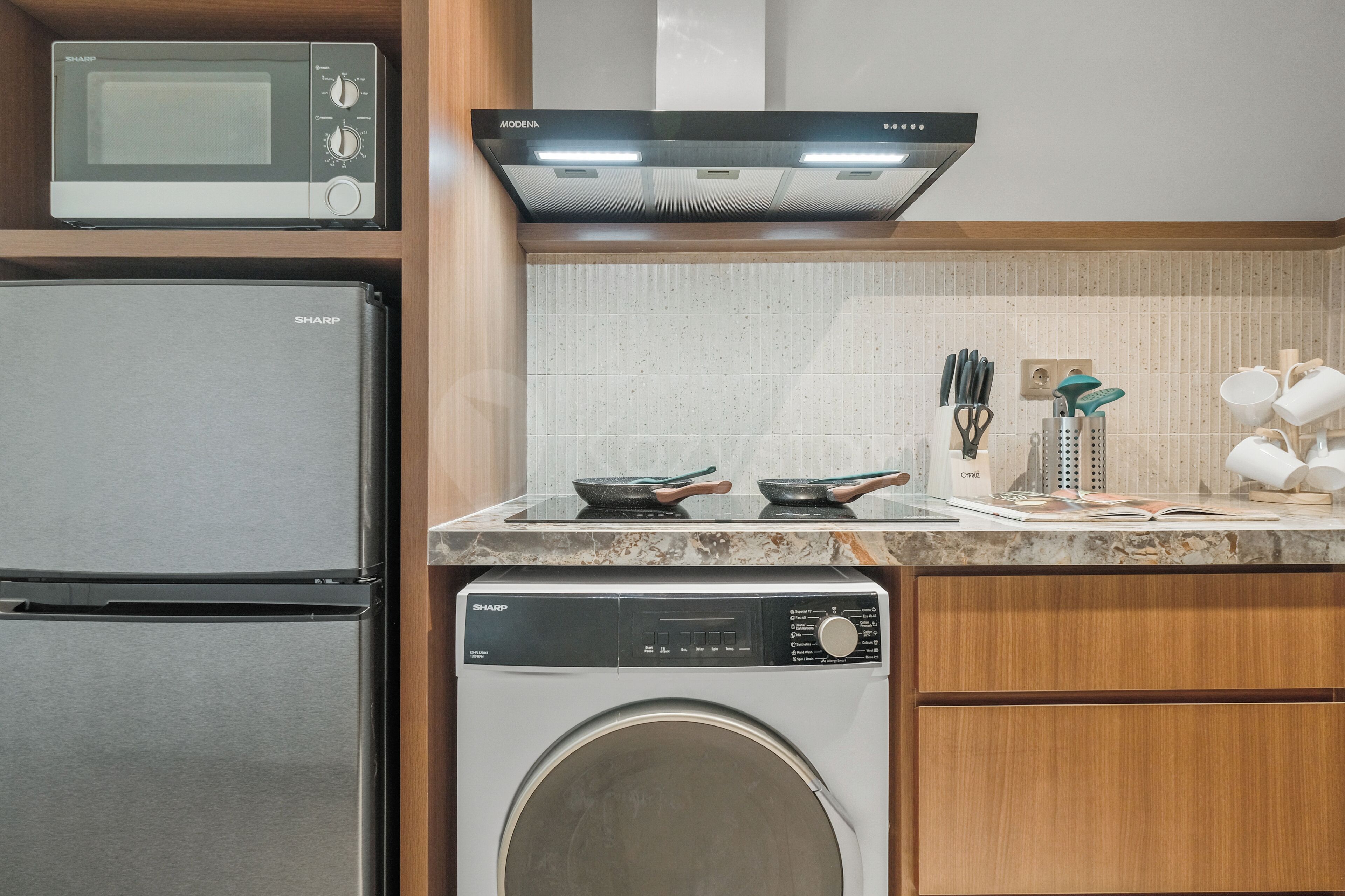 Una cocina compacta equipada con microondas, un refrigerador de acero inoxidable, lavadora y estufa con campana extractora.