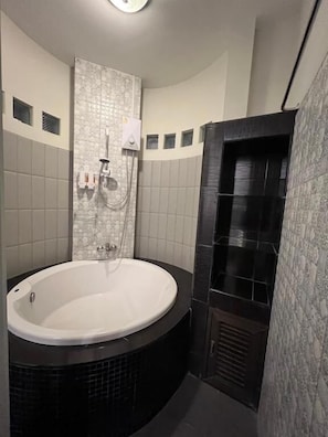 A bathroom with a large bathtub, a shower area, and tiled walls.