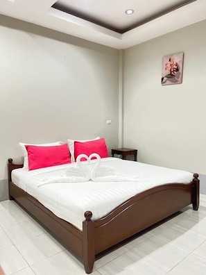 A neatly made bed with a headboard, a bedside table, and a wall-mounted picture.
