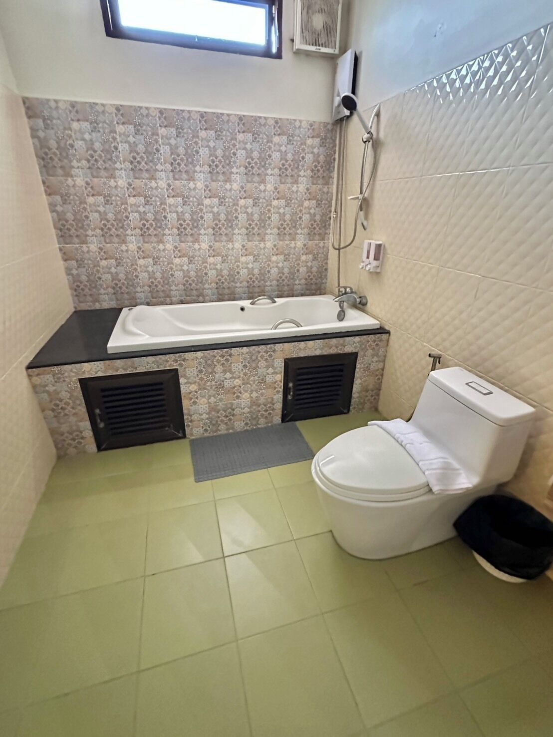 A bathroom with a bathtub, toilet, and a window.