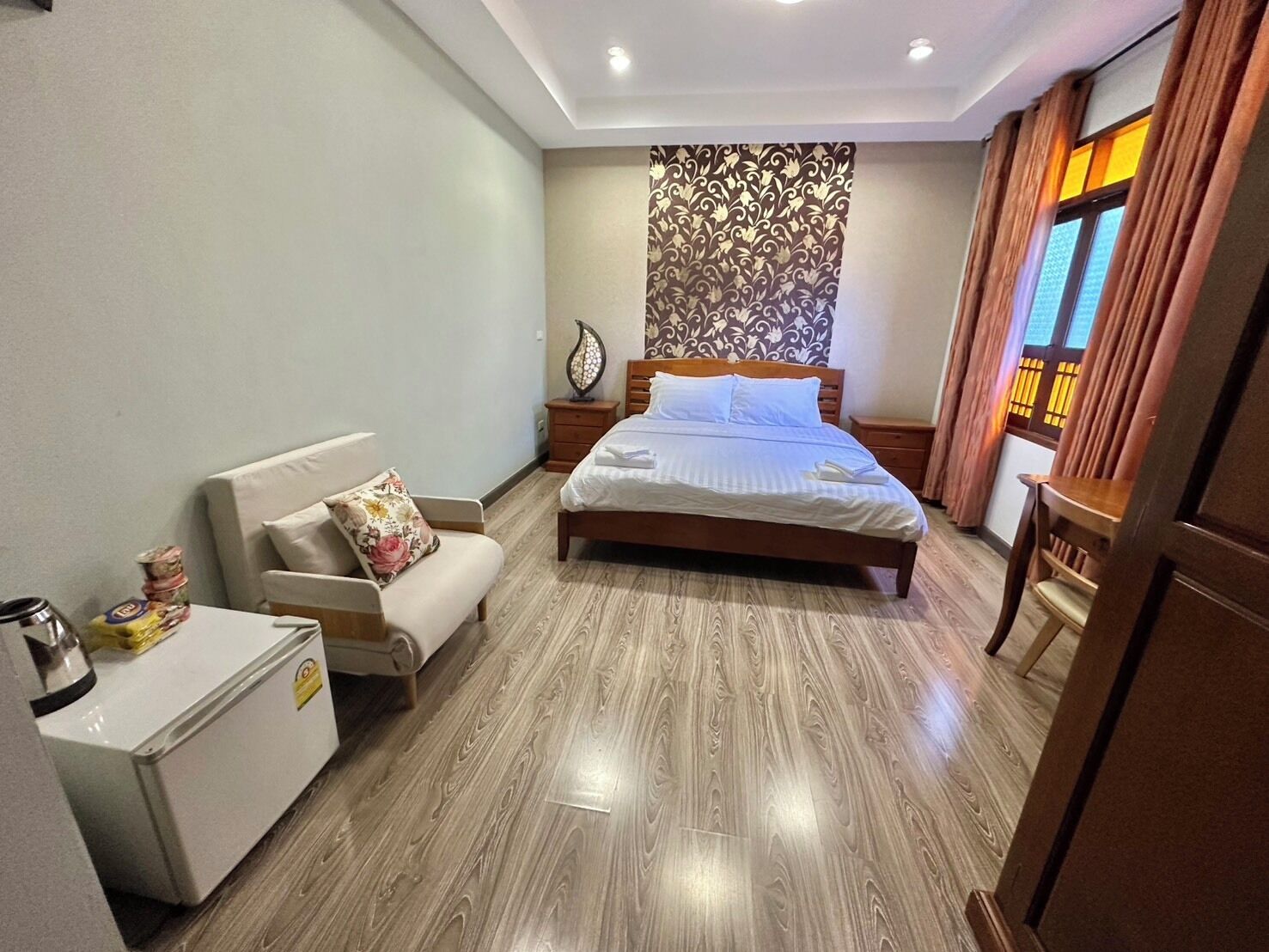 Una habitación de hotel con cama, sofá, mesita de noche y una pequeña mesa con refrigerador.