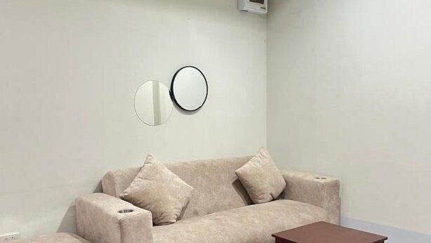 A living room with a sofa, a coffee table, and a wall-mounted air conditioning unit. - Excellence Pool Villa (Pattaya)