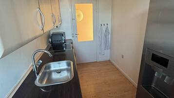 A compact kitchen with a sink, a microwave, and a refrigerator.
