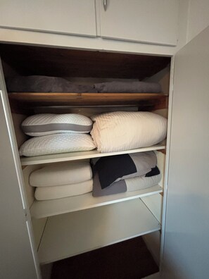 Ein Schrank mit Regalen, gefüllt mit gefalteten Decken und Kissen.