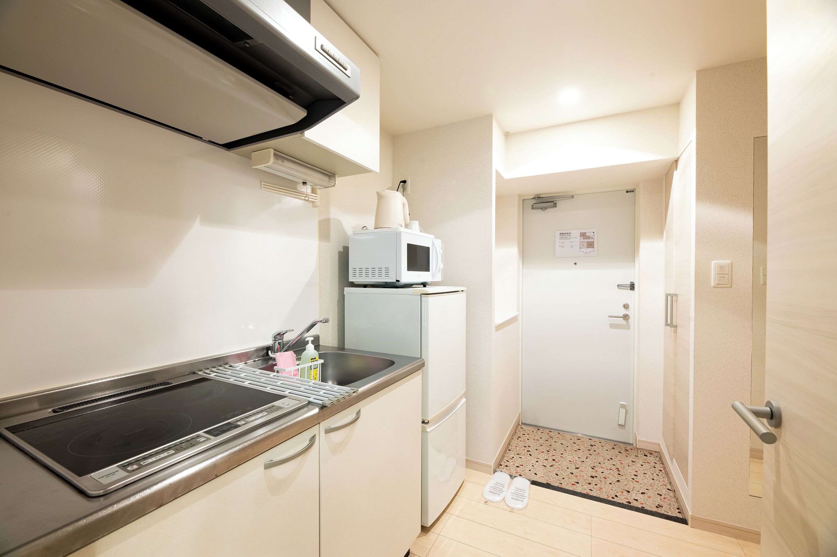 A compact kitchen with a built-in stove, a microwave, and a refrigerator.