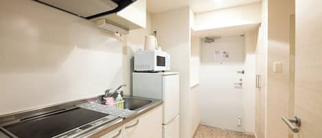 A compact kitchen with a built-in stove, a microwave, and a refrigerator.