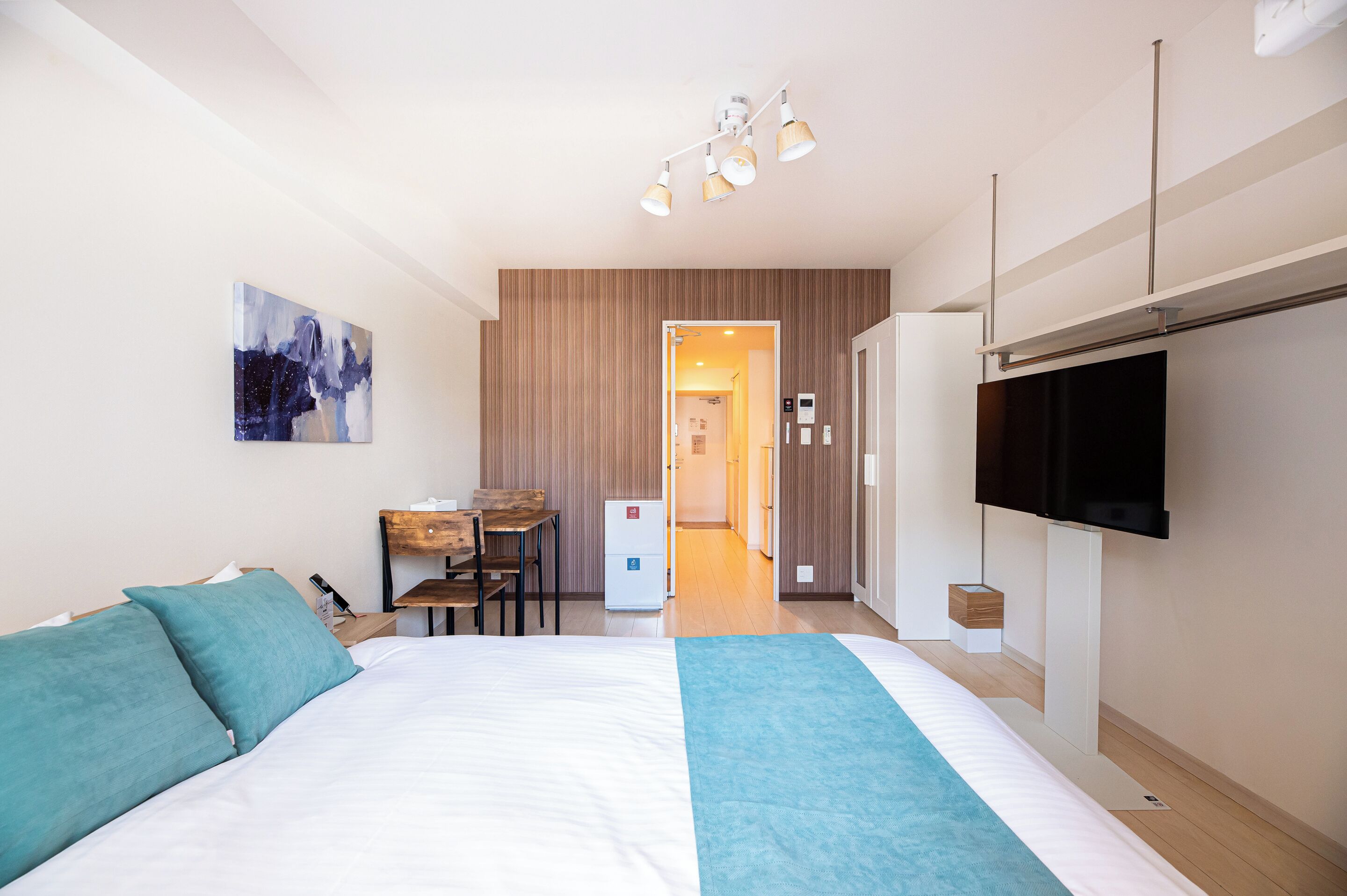 Una habitación de hotel con una cama, un escritorio, un televisor y una puerta que da a otra habitación.