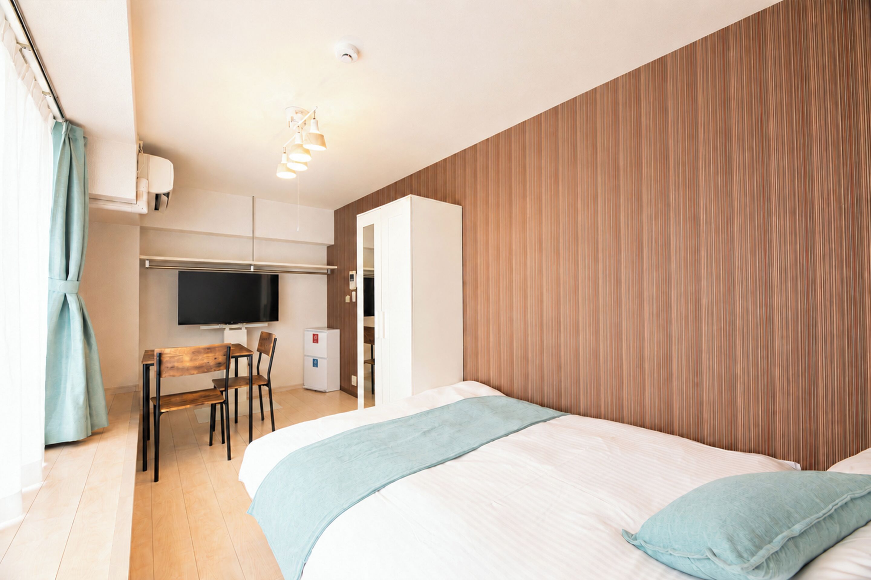 Une chambre d’hôtel comprenant un lit, un bureau avec une chaise, une télévision et une armoire.