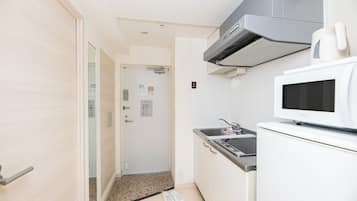 A compact kitchen with a microwave, sink, and a door leading to a hallway.