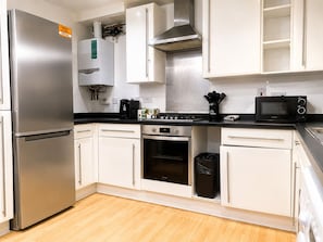 Eine moderne Küche mit Edelstahlgeräten, weißen Schränken, einer schwarzen Arbeitsplatte und einem sichtbaren Mülleimer.