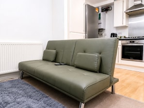 Eine moderne Küche mit Backofen und ein graues Sofa im Wohnbereich.