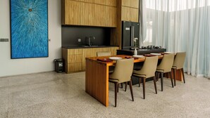 Una cocina moderna con armarios de madera, un refrigerador negro y un comedor con mesa y sillas de madera.