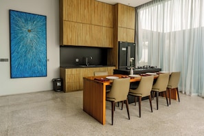 Eine moderne Küche mit Holzschränken, einem schwarzen Kühlschrank und einem Essbereich mit Holztisch und Stühlen.