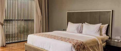Un dormitorio moderno con una cama grande, cabecera y una ventana con persianas.