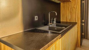 Una cocina moderna con un lavamanos de acero inoxidable, paneles de madera y encimera negra.