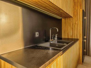 Eine moderne Küche mit Spüle aus Edelstahl, Holzvertäfelung und einer schwarzen Arbeitsplatte.