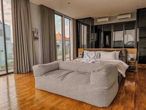 Ein modernes Hotelzimmer mit einem großen Bett, einem Sofa, einem Kleiderschrank und einem großen Fenster mit Blick auf die Stadt.