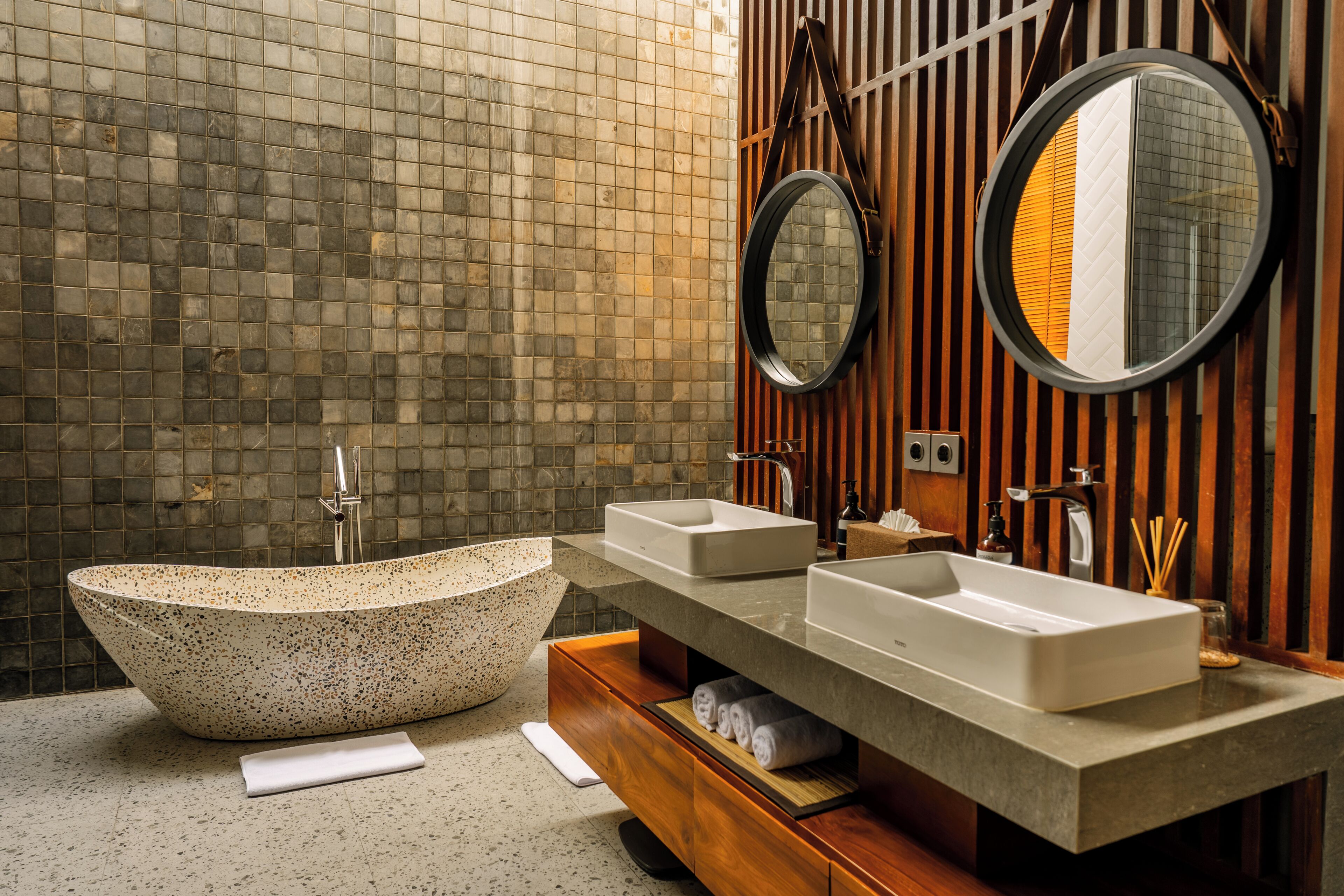 Une salle de bain avec une baignoire sur pieds, deux vasques, un meuble-lavabo en bois et un miroir.
