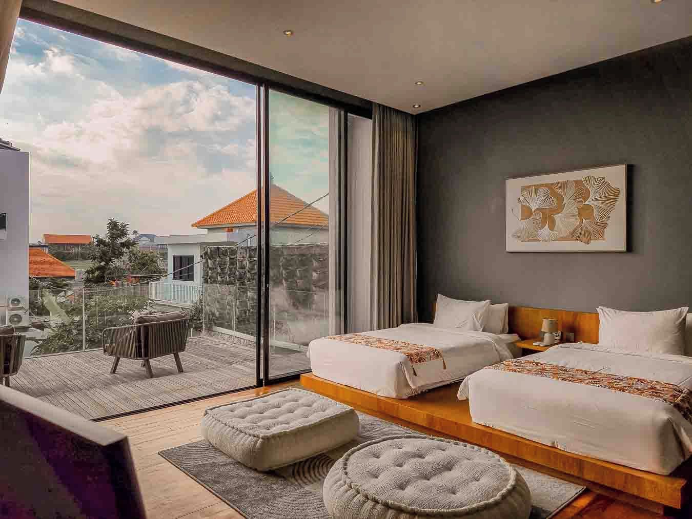 Een moderne hotelkamer met balkon, twee bedden, een groot raam en uitzicht op de stad.