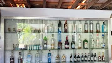 Zona de bar con techo de madera y vitrina de vidrio llena de diferentes botellas de licor.