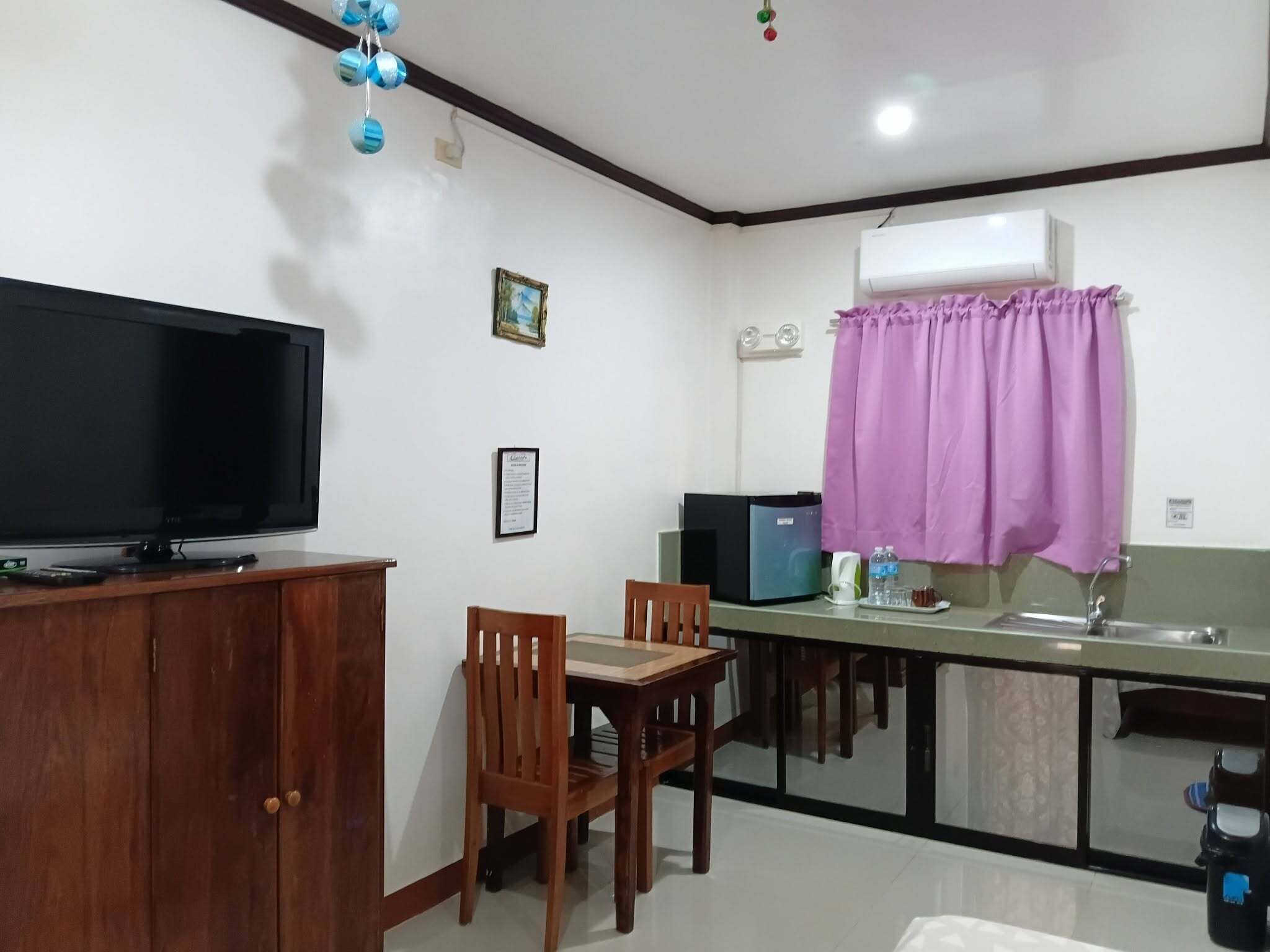 Un espacio habitable compacto con televisor, una pequeña mesa de comedor y una zona de kitchenette.