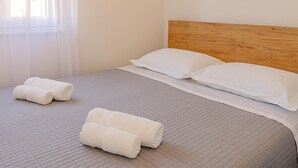 A neatly made bed with a wooden headboard, white pillows, and rolled white towels. - Apartment With Balcony And Parking 2, Okrug Gornji, Croatia (Okrug Gornji)