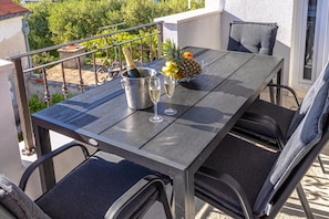 Ein Balkon mit Tisch für zwei Personen, komplett mit einer Champagnerflasche, zwei Gläsern und einer Obstschale mit Ananas und Orangen.