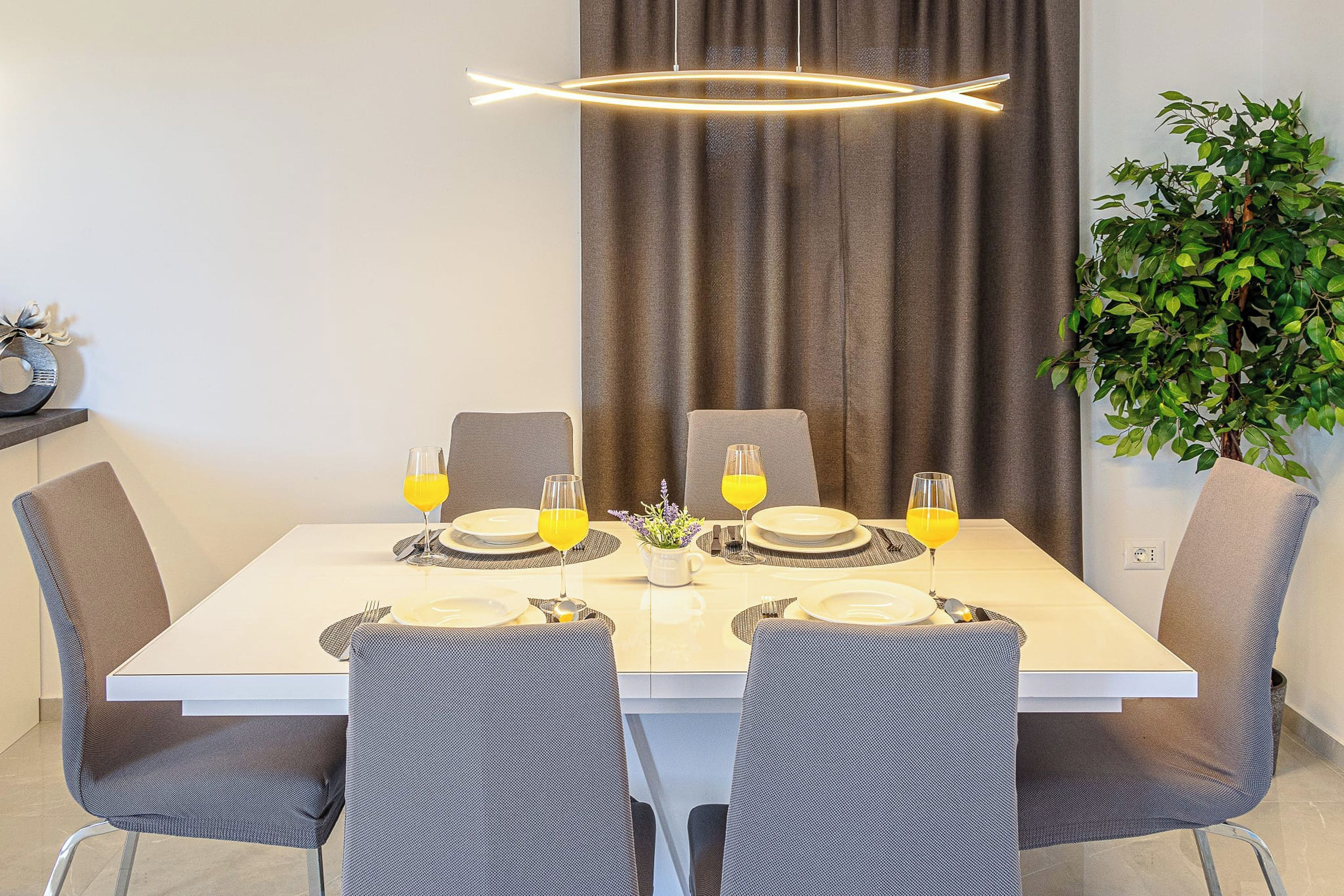Une table à manger dressée avec des assiettes, des verres et un vase de fleurs.