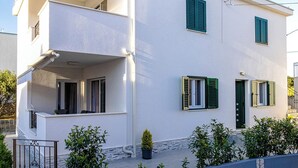 A two-story building with a balcony on the upper floor, a door with a green shutter, and a small potted plant in the foreground. - Apartment With Balcony And Parking 2, Okrug Gornji, Croatia (Okrug Gornji)