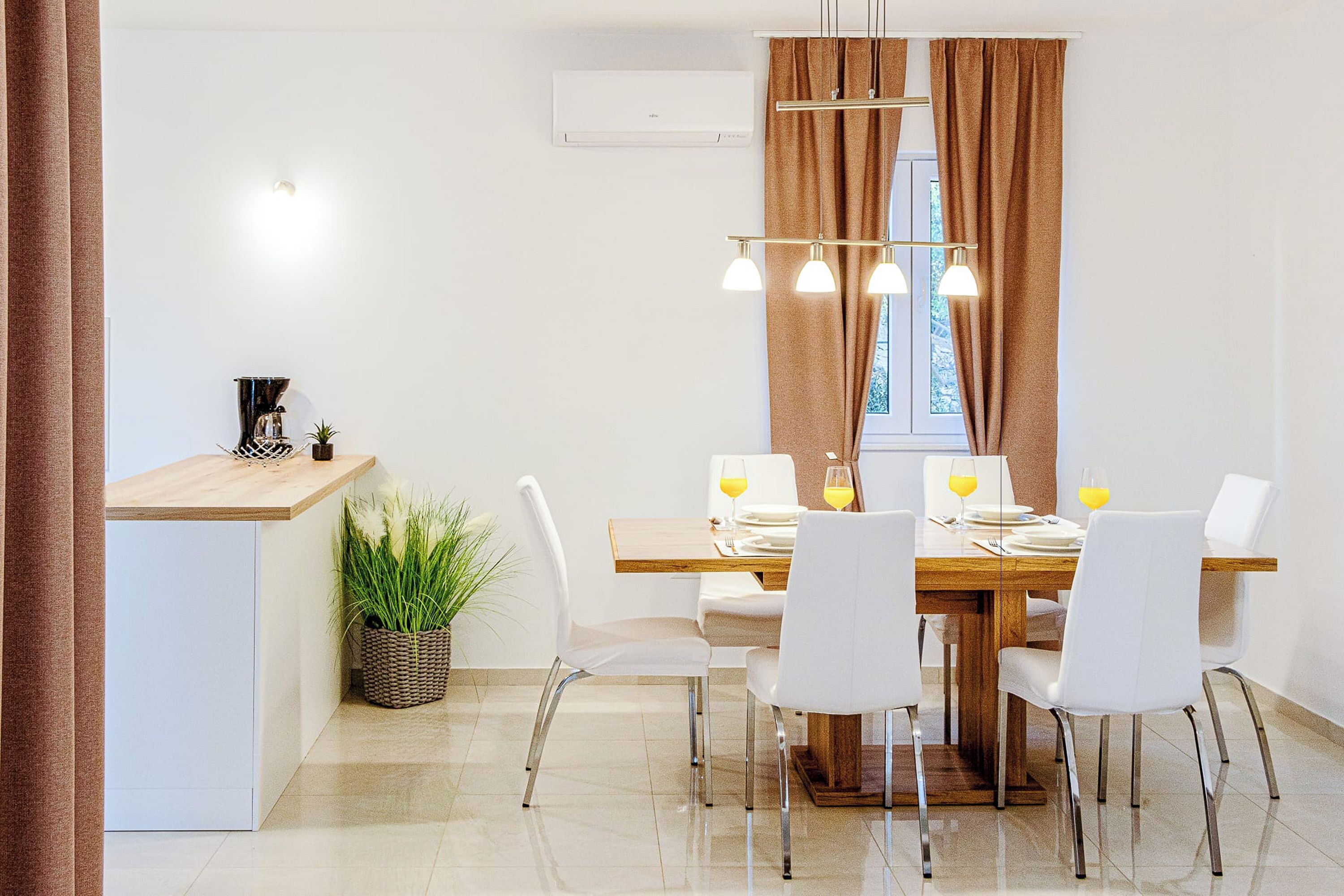 A modern dining area with a wooden table, white chairs, and a built-in kitchen counter.