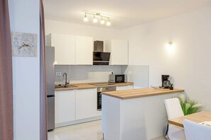 Eine moderne Küche mit weißen Schränken, einer Holz Arbeitsplatte, einem eingebauten Backofen und einer Mikrowelle.