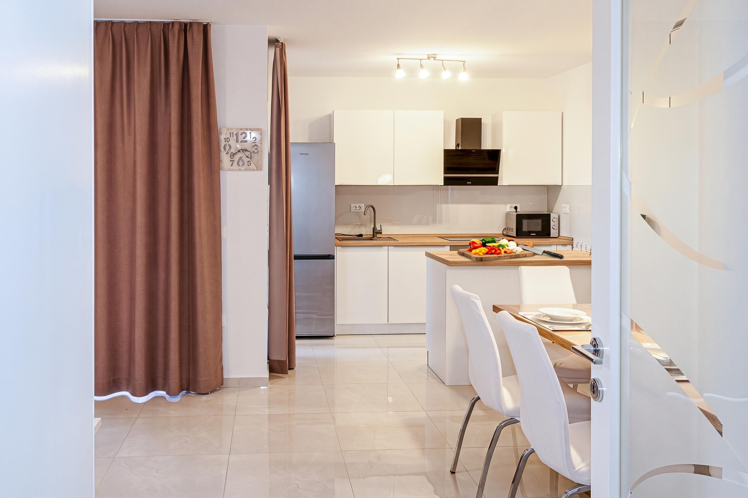 Een moderne keuken met witte kasten, een roestvrijstalen koelkast en een magnetron op het aanrecht.