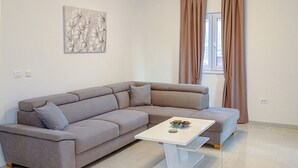 A modern living room with a grey sectional sofa, a white coffee table, and a painting on the wall. - Apartment With Balcony And Parking 1, Okrug Gornji, Croatia (Okrug Gornji)