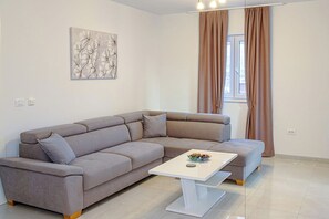 Ein modernes Wohnzimmer mit einem grauen Ecksofa, einem weißen Couchtisch und einem Gemälde an der Wand.