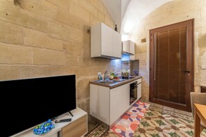 A compact kitchen with a TV, a sink, and a wooden door. - NonnAnna Apartment In Martano Historic Centre, Martano, Italy (Martano)