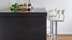 Moderni baaritiski, jossa on musta työtaso, mustavalkoinen kehystetty valokuva sekä valikoima pientä purtavaa ja juomia.