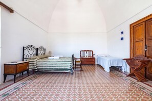 Ein Schlafzimmer mit einem Bett, Nachttischen, einem Holzschrank, einem Stuhl und einem Tisch mit Tischdecke.