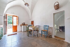 Ein Essbereich mit Tisch und Stühlen, einem Kühlschrank und einer Tür, die nach draußen führt.