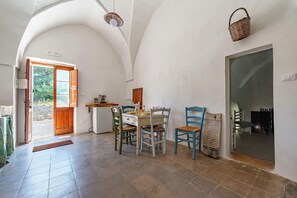 Ein Essbereich mit Tisch und Stühlen, einer Tür, die nach draußen führt, und einem Korb an der Wand.