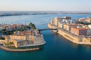 Eine Küstenstadtlandschaft mit einer markanten historischen Festung, modernen Gebäuden und freiem Blick auf das Meer.