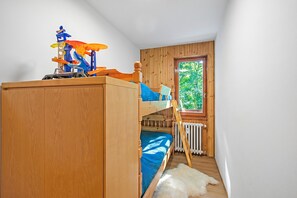 A bunk bed with a play structure on top, a wooden wardrobe, a white furry rug, and a window with a view of greenery. - L'Anemone near Campo Smith Lifts, Bardonecchia, Italy (Bardonecchia)