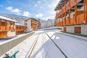 A snow-covered street with modern buildings, a clear sky, and mountains in the background. - L'Anemone near Campo Smith Lifts, Bardonecchia, Italy (Bardonecchia)