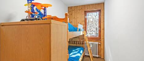 A bunk bed with a toy car and a window with a view of trees.