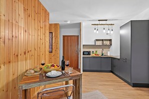 A modern kitchen with grey cabinets, a wooden dining table, and a fruit bowl. - L'Anemone near Campo Smith Lifts, Bardonecchia, Italy (Bardonecchia)