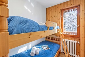 A bunk bed room with a wooden headboard, a window with a view of snow-covered trees, and a radiator. - L'Anemone near Campo Smith Lifts, Bardonecchia, Italy (Bardonecchia)
