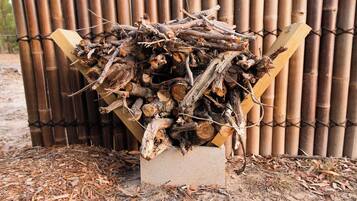 A pile of firewood stacked in a concrete block against a bamboo fence.