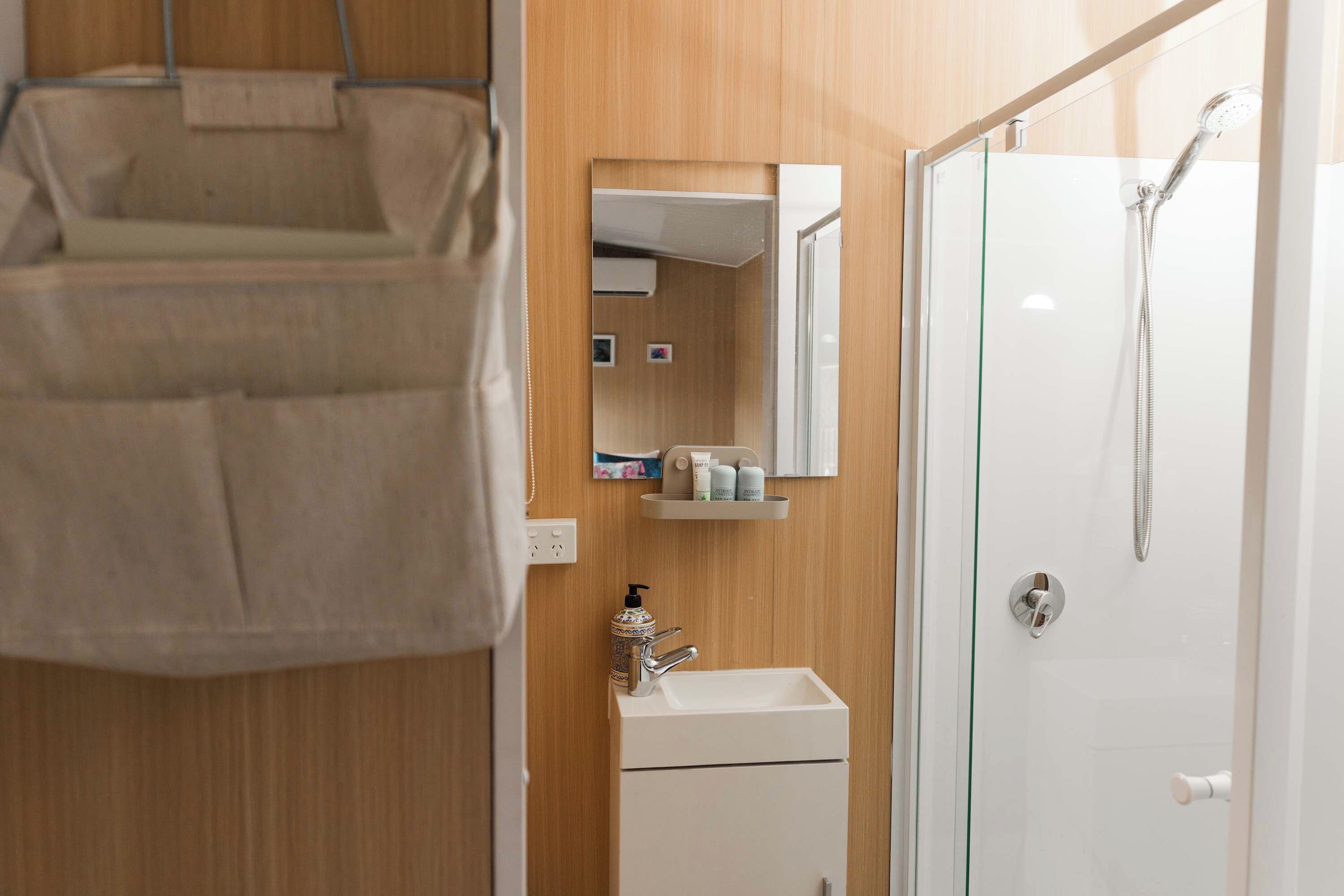 A bathroom with a shower, a sink, a mirror, and a towel rack.